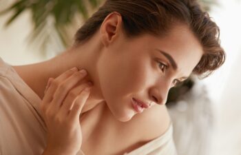 Beauty Face. Portrait Of Woman Touching Neck And Looking Away. Beautiful Model Enjoying Radiant And Glowing Facial Skin. Tender Brunette With Natural Makeup.